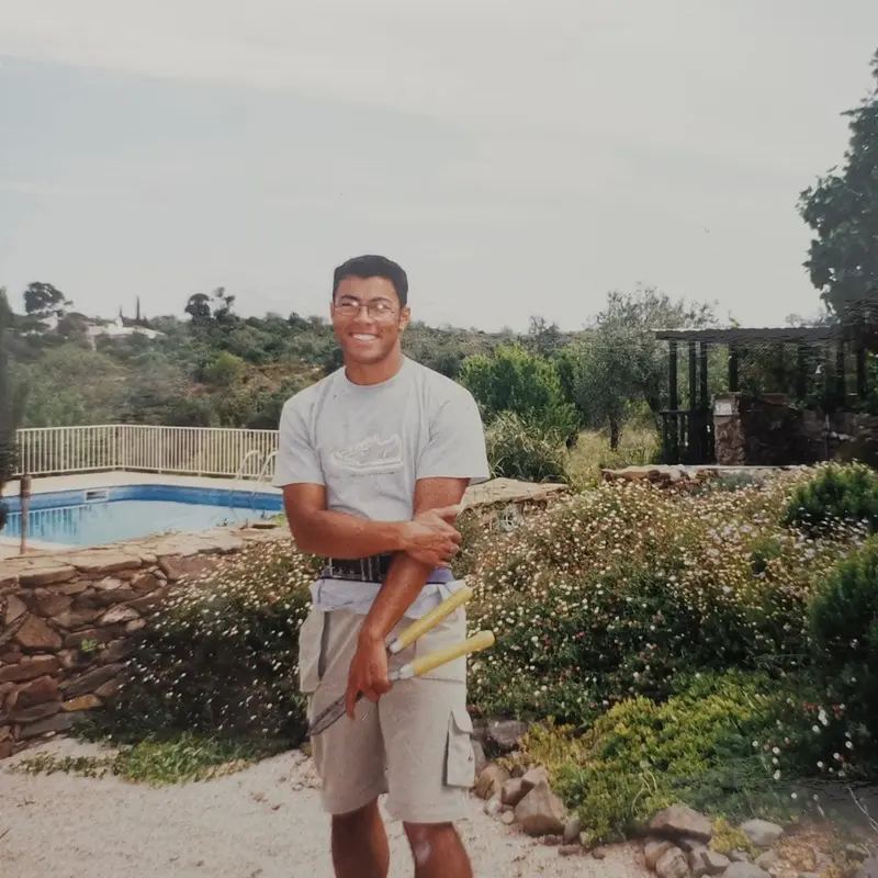 Fotografia de arquivo: jardineiro com tesoura de sebes junto a piscina e rochas