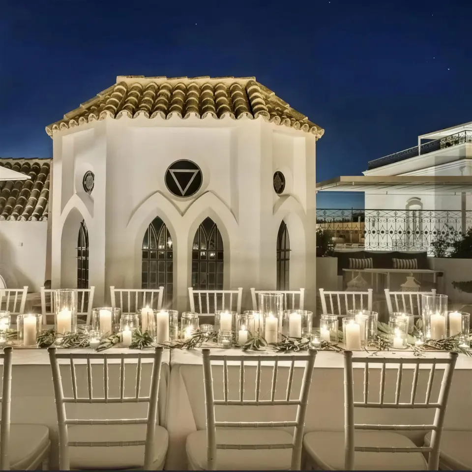 Torreão iluminado atrás de mesa posta com velas, ao anoitecer