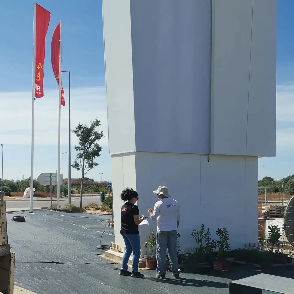 Dois membros da equipa a rever o plano de plantação junto ao letreiro do centro comercial