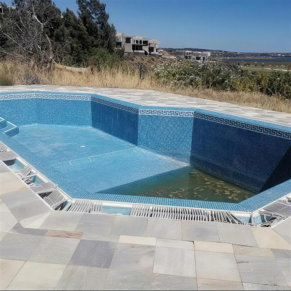 Piscina vazia com mosaico antigo danificado, antes da renovação