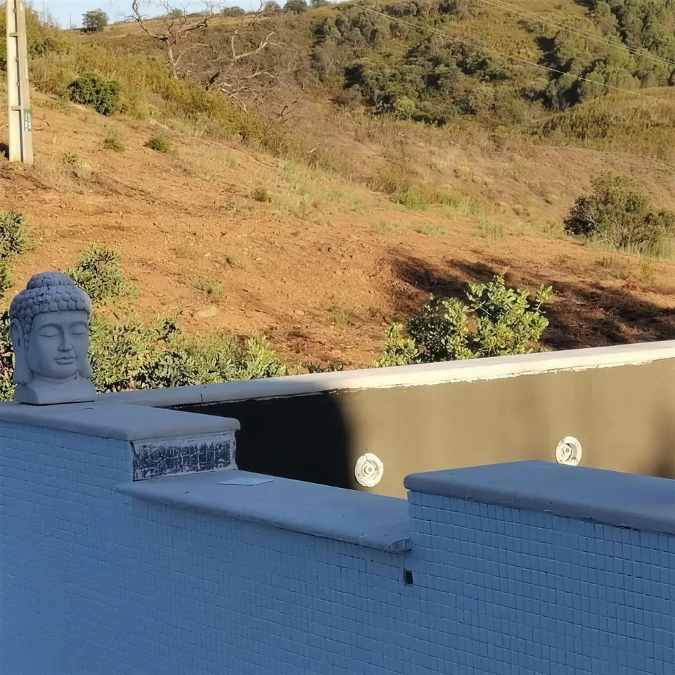Cabeça de Buda sobre a parede da piscina com mosaico azul novo