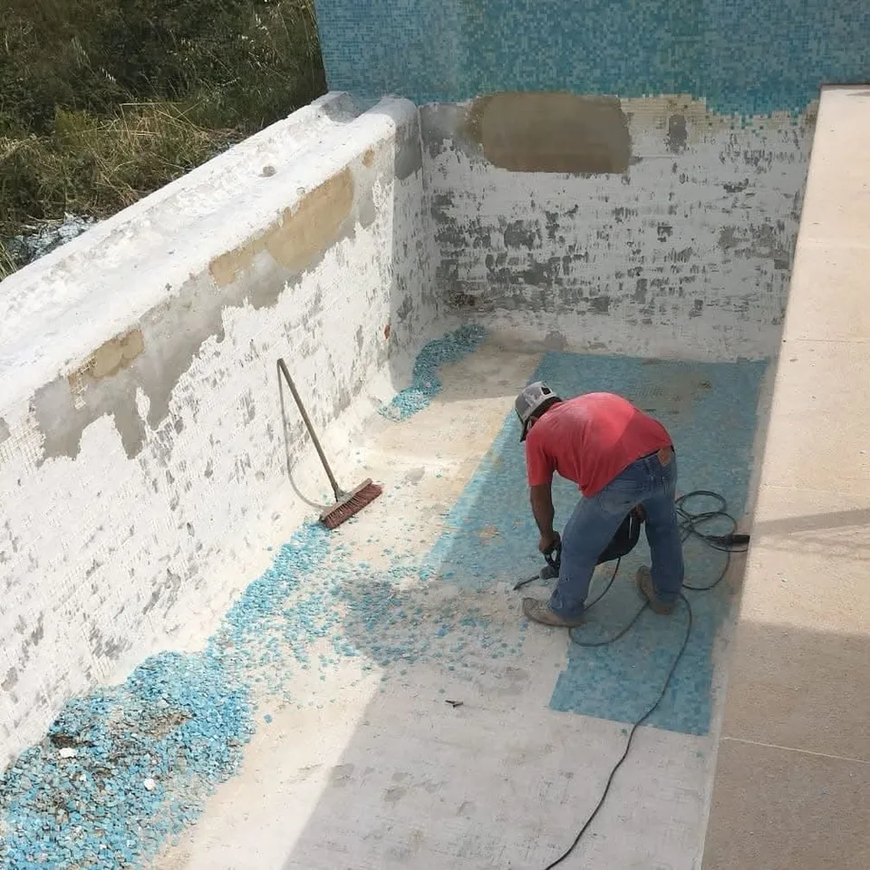 Trabalhador a picar o revestimento antigo de uma piscina em obra