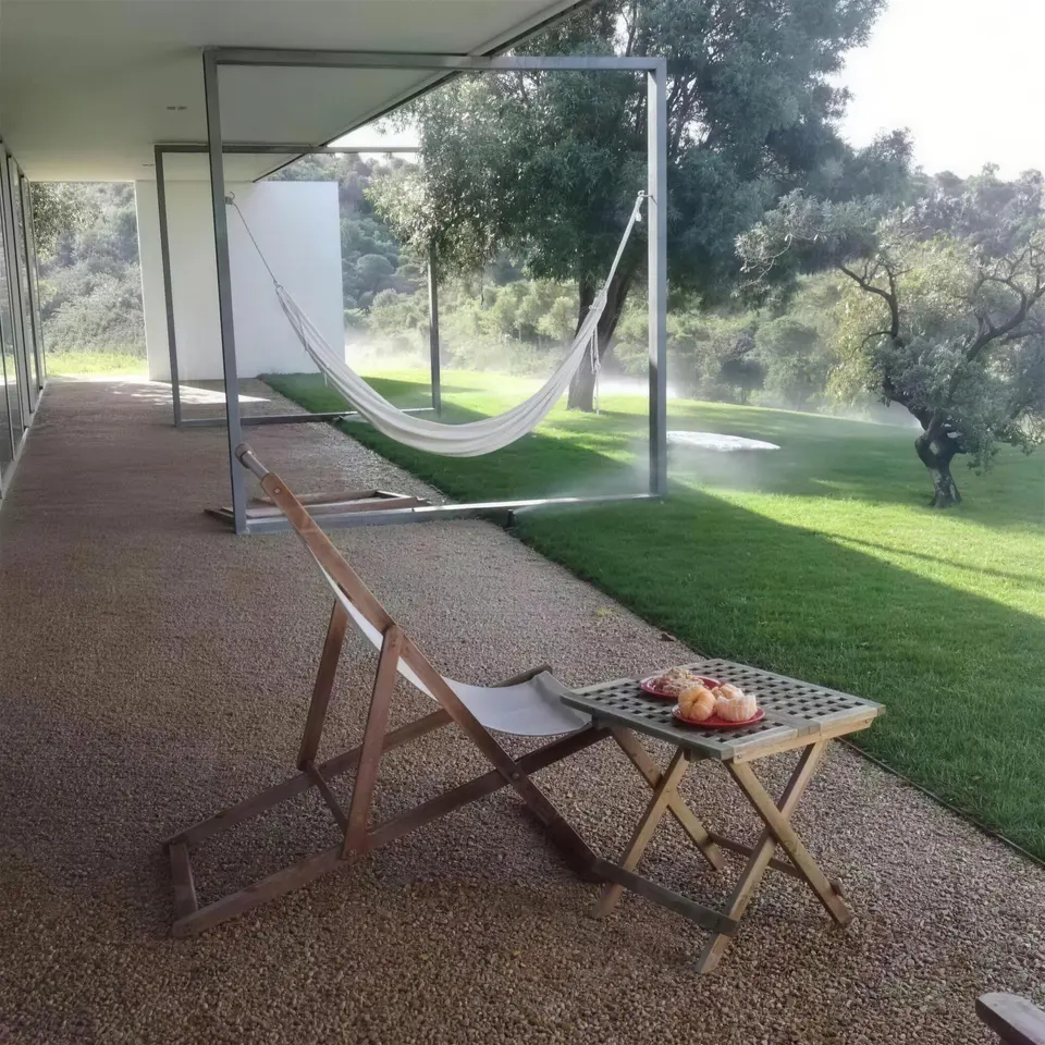 O mesmo jardim com relvado verde, redes de descanso e nebulização