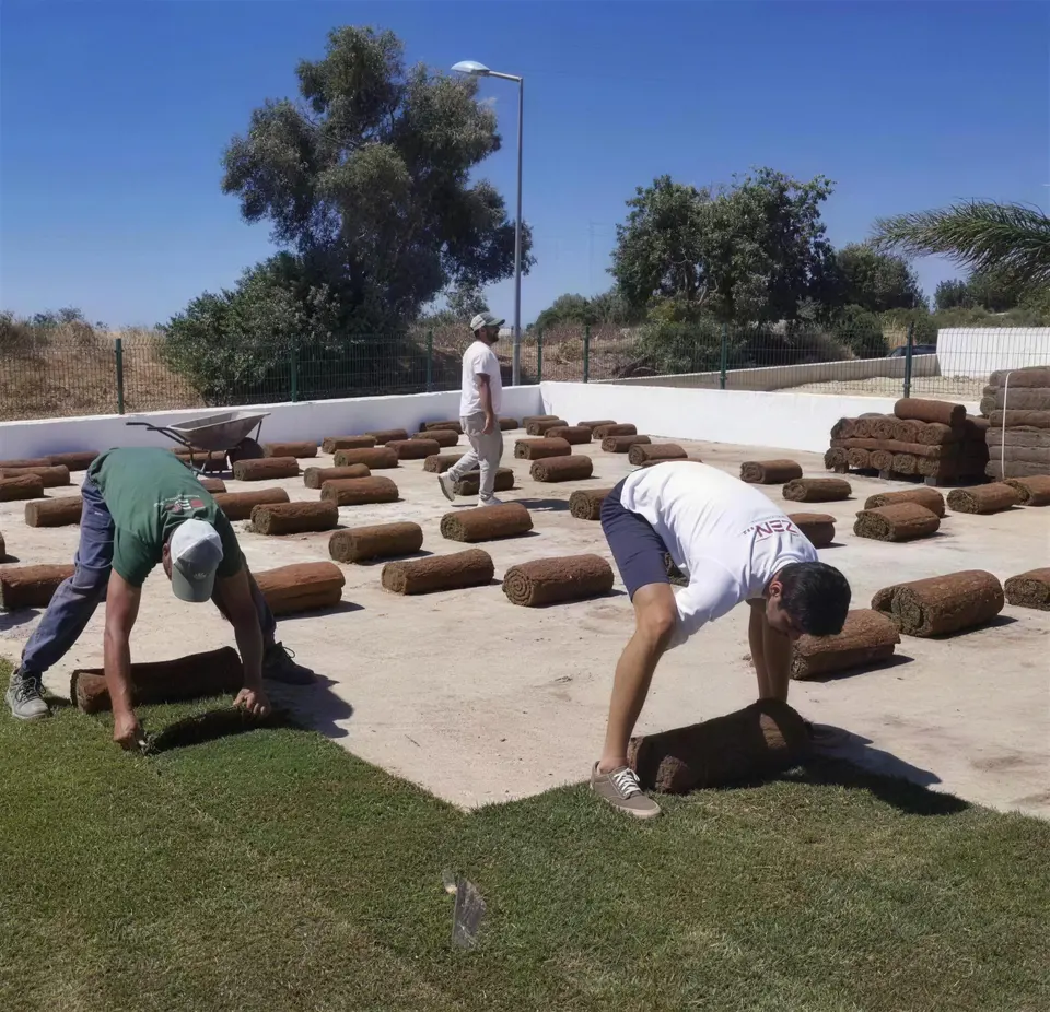 Equipa a estender rolos de relva num terraço preparado