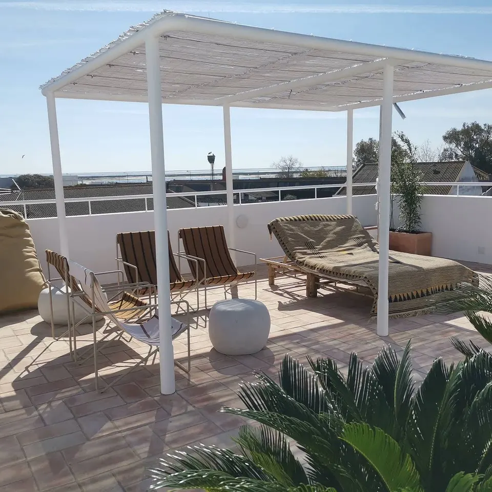 Terraço com pérgola branca, espreguiçadeiras e cica, com vista para a ria