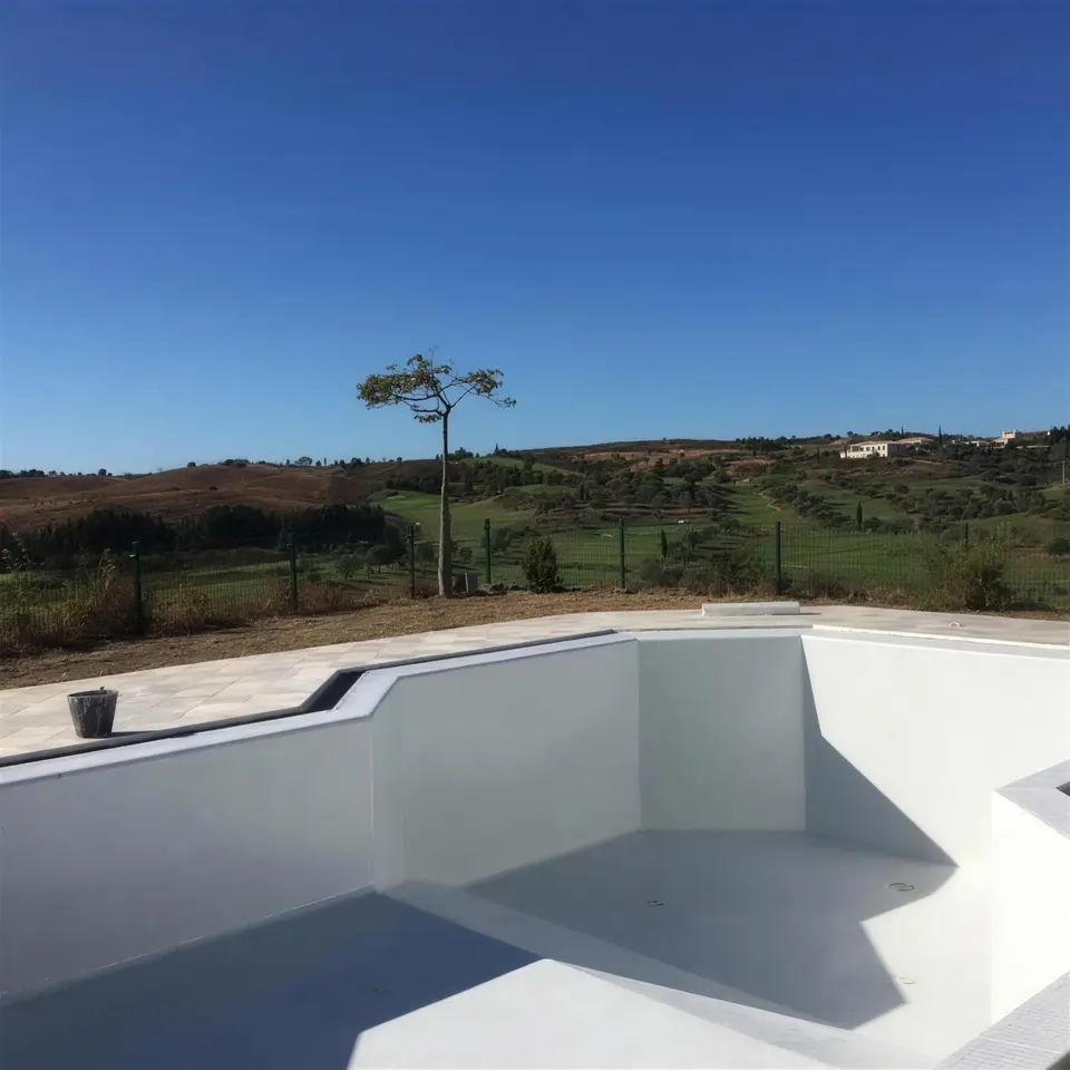Tanque de piscina renovado em branco, sobre um vale verde